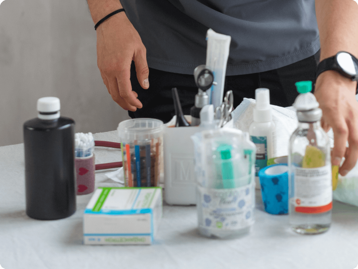 A person is standing in front of some medicine and other items.