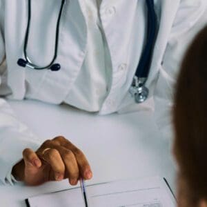 A person in white lab coat sitting at table.