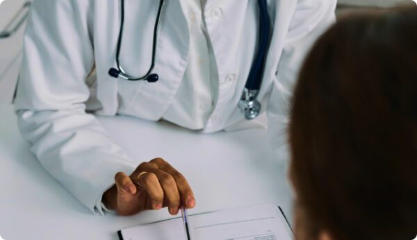 A person in white lab coat sitting at table.